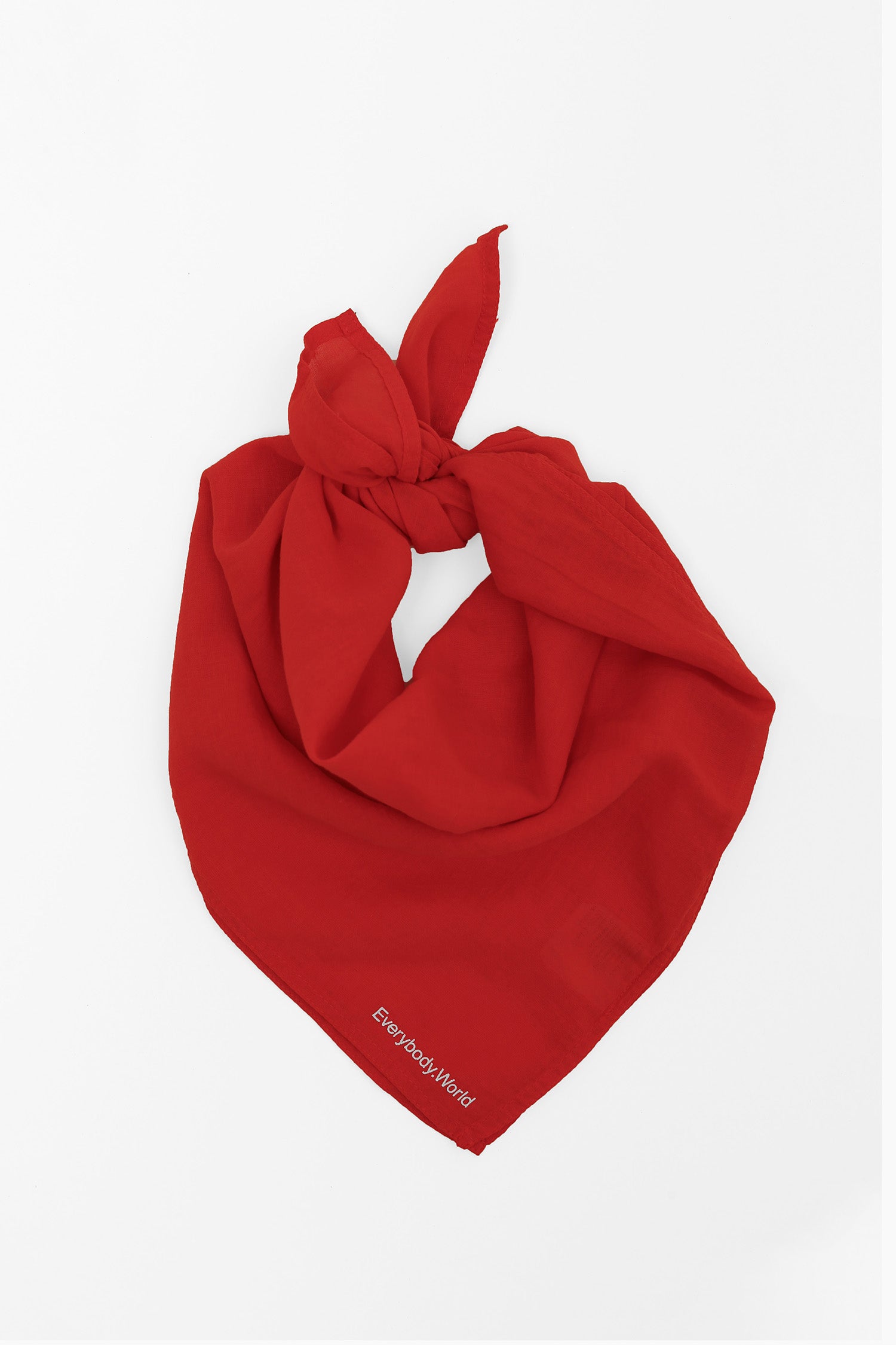 Lava colored scarf tied in a knot on a light gray background.