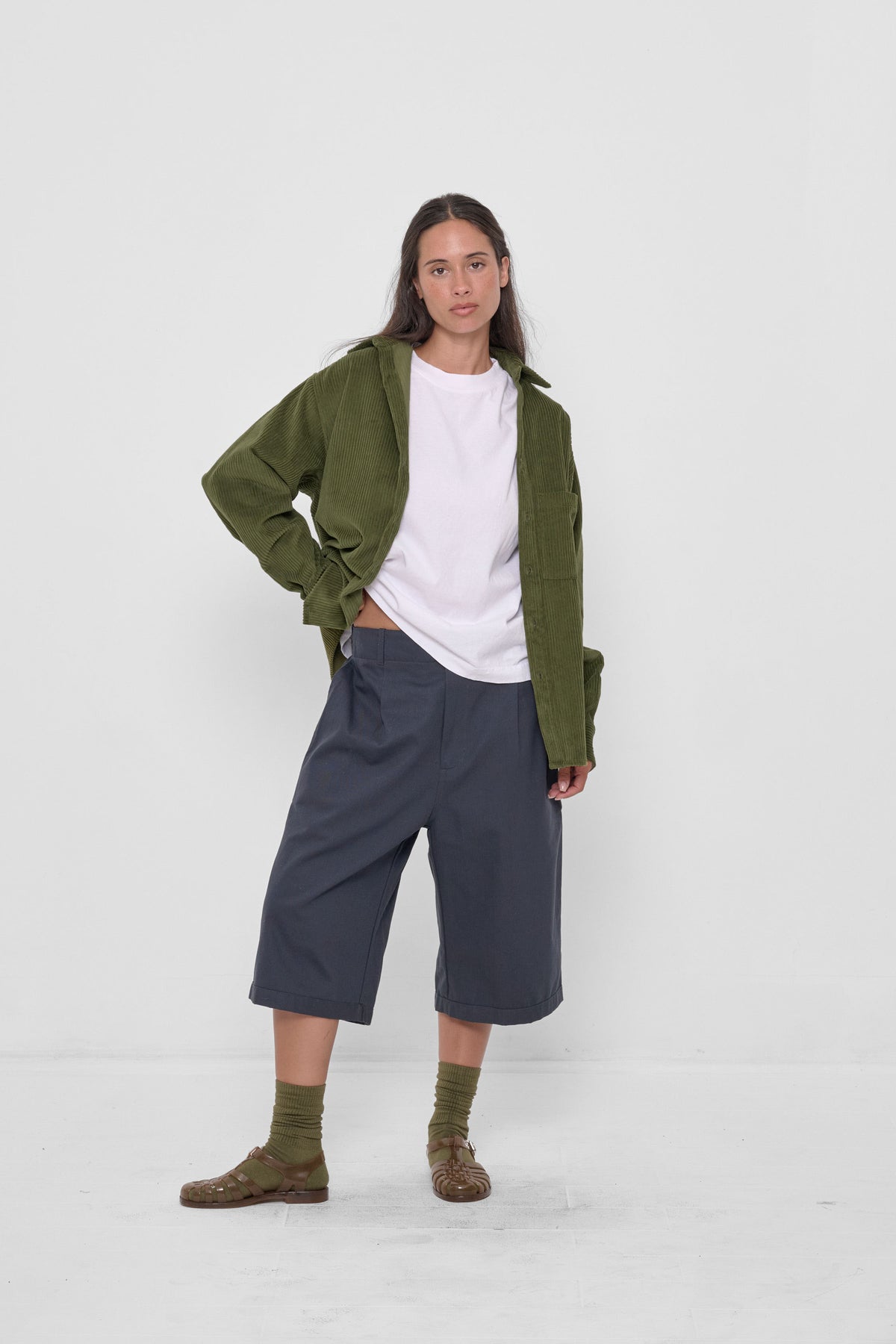 Bermuda Shorts in Slate – on model, styled with Olive Cord Button-Up Shirt, Olive Squishy Socks, and Plasticana sandals