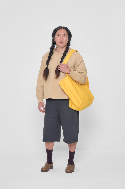 Man holding it over his shoulder, showing that the bag opening begins at his mid-torso.