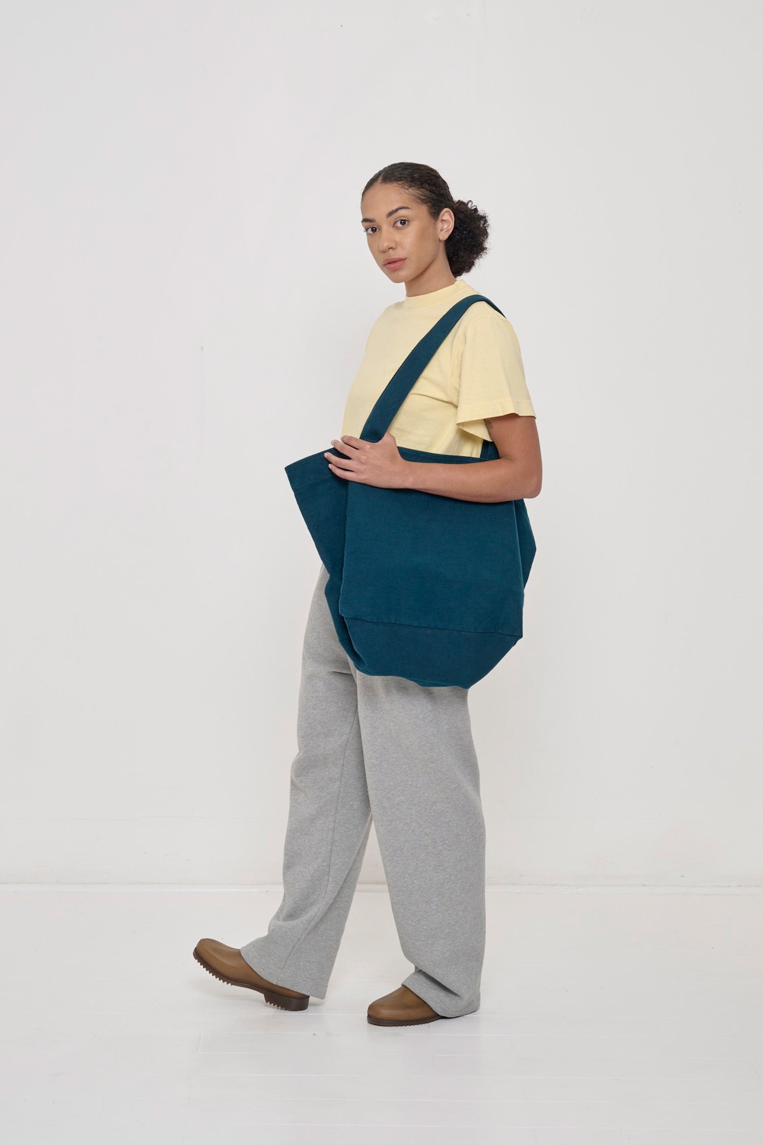 Woman holding Big Tote in Juniper dark teal on her shoulder, showing fabric folds and the flexibility of the bag.