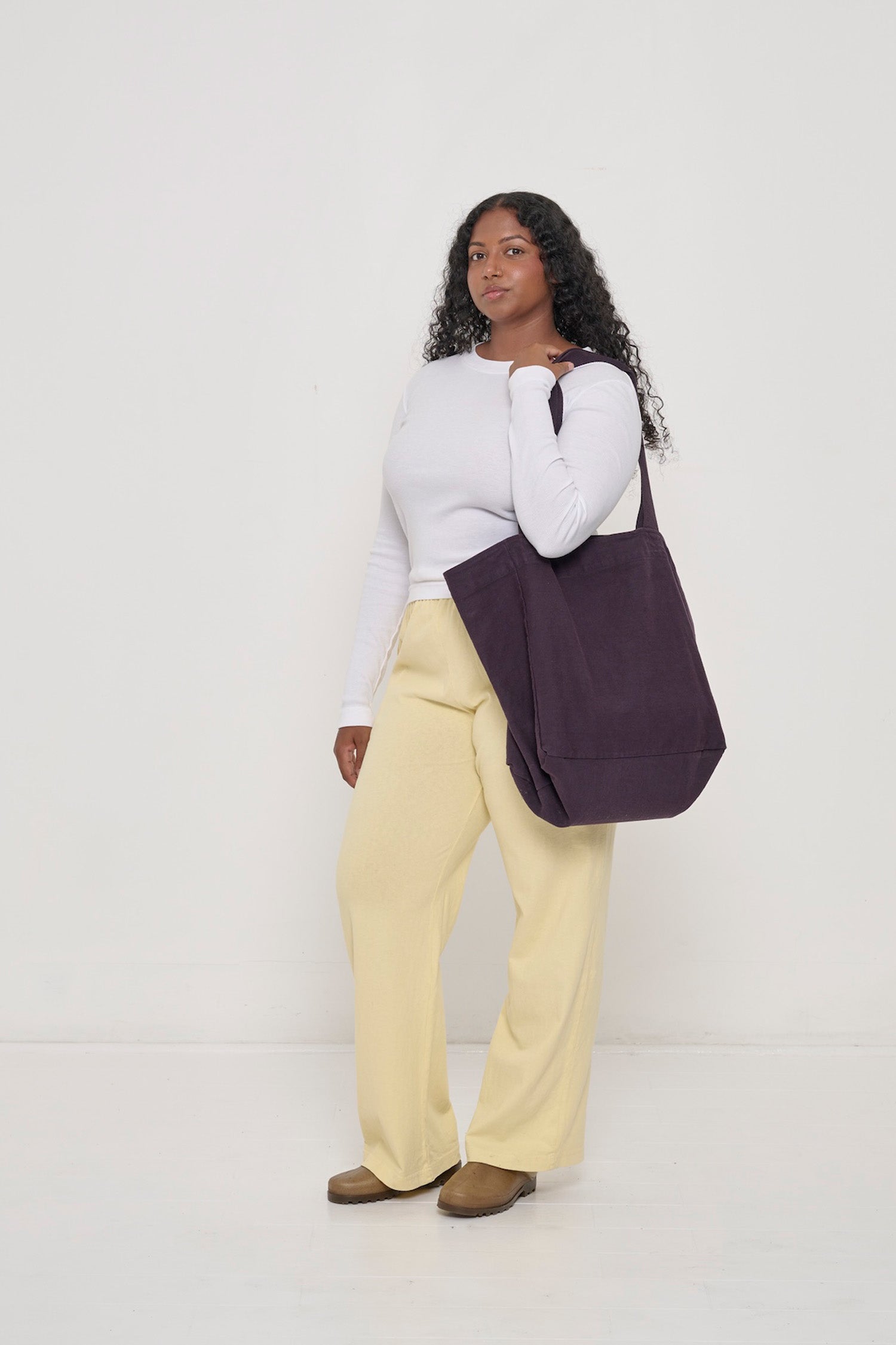 Woman holding Big Tote in Mulberry dark purple on her shoulder, showing fabric folds and the flexibility of the bag.