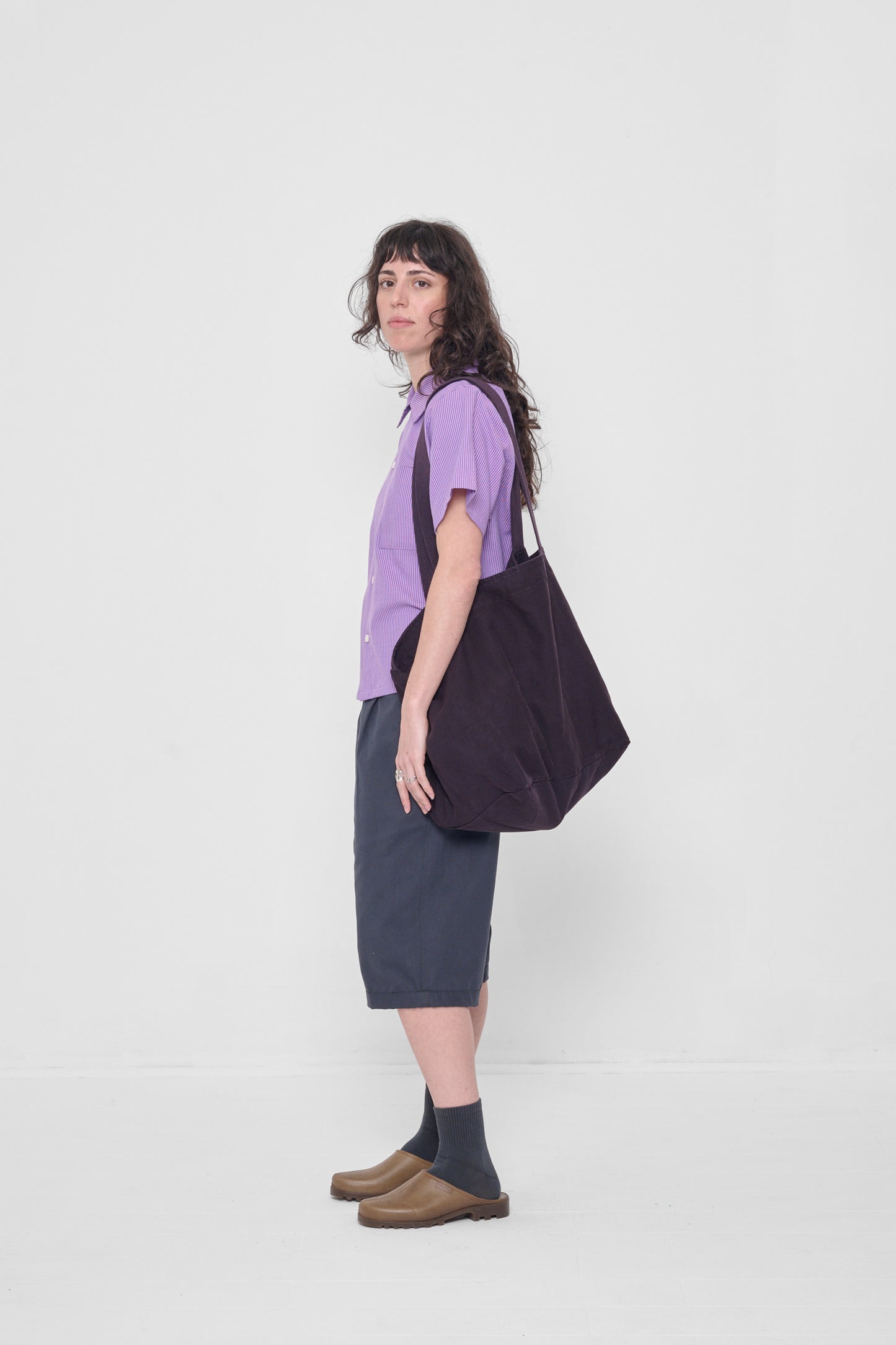 Woman holding it over his shoulder, showing that the bag opening begins at her mid-torso.