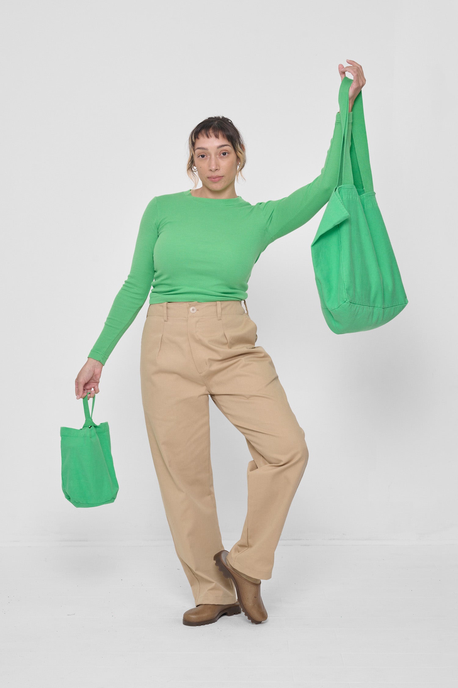 Woman holding Big Tote and Loop Tote out from her body showing the size comparison. 