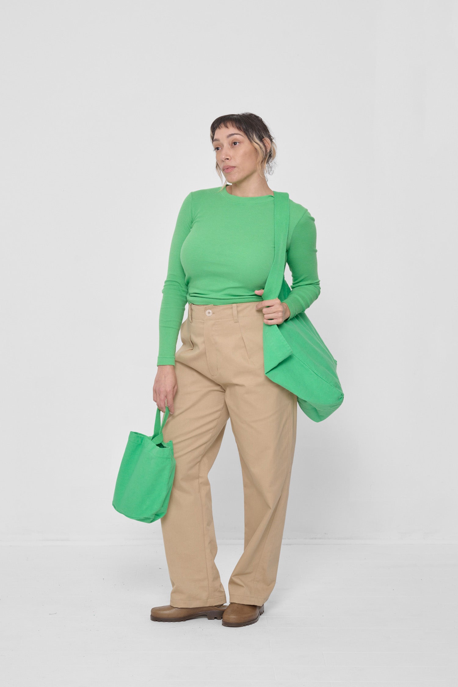 Woman holding it over his shoulder, showing that the bag opening begins at her mid-torso.