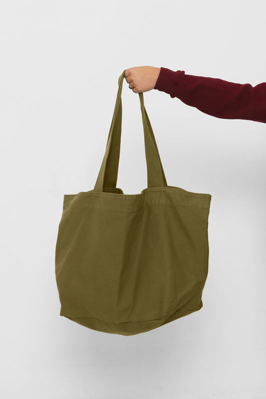 Big Tote in Olive, held in a person's hand, showing gussets, depth and stitching.