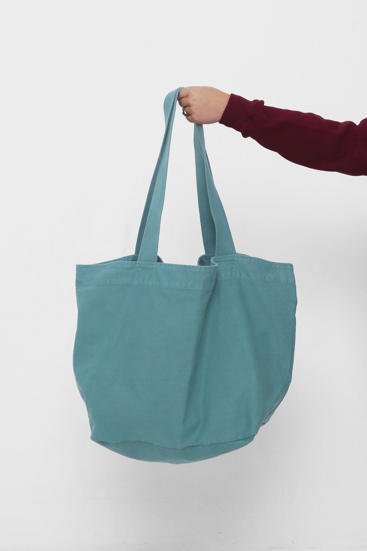 Big Tote in Oyster, held in a person's hand, showing gussets, depth and stitching.