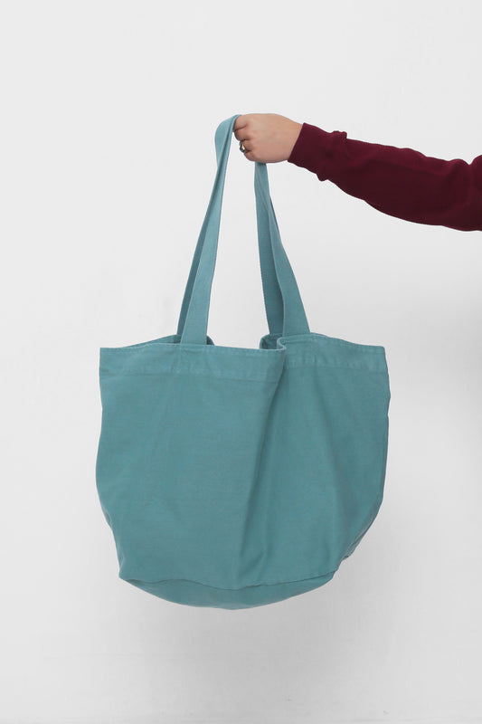 Big Tote in Oyster, held in a person's hand, showing gussets, depth and stitching.