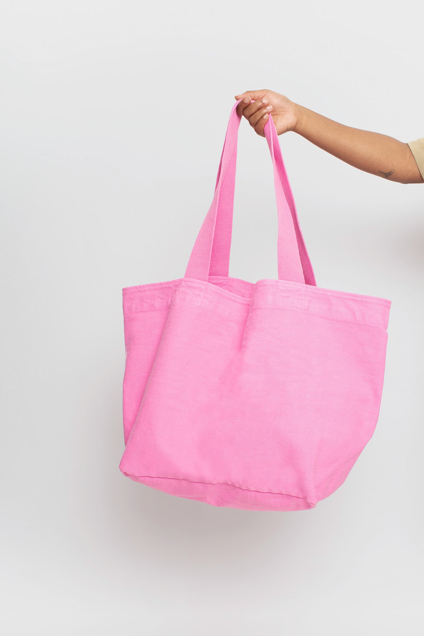 Big Tote in Pixie light pink, held in a person's hand, showing gussets, depth, stitching, and web straps.