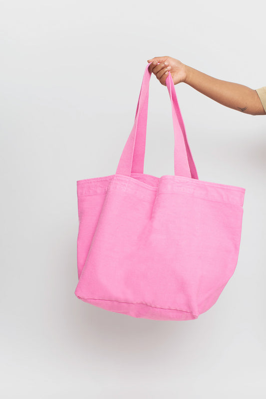 Big Tote in Pixie medium pink, held in a person's hand, showing gussets, depth, stitching, and web straps.