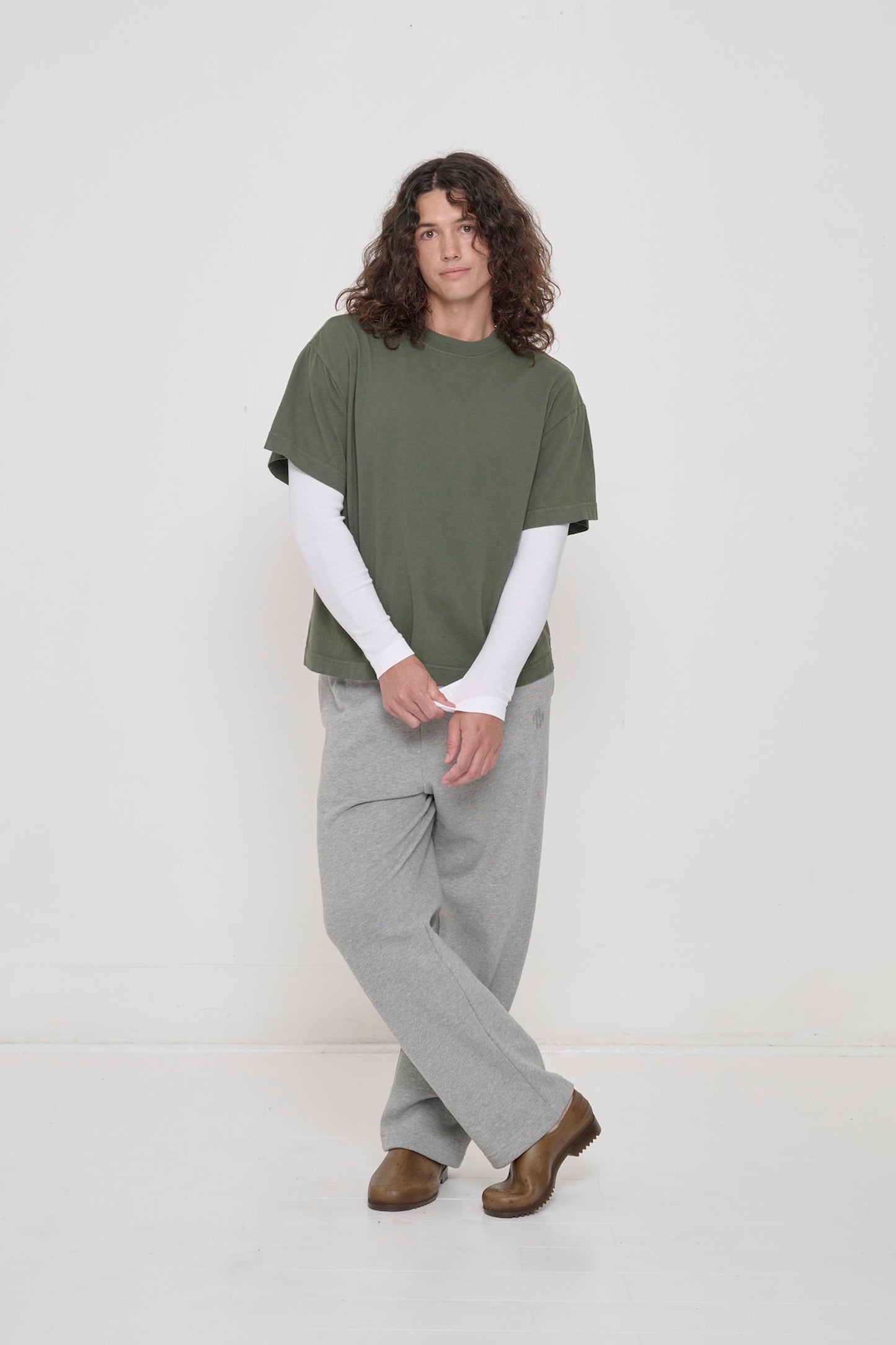 A person in a Pine Boxier Trash Tee over a White Rib Long Sleeve, pulling the long sleeve's cuff.