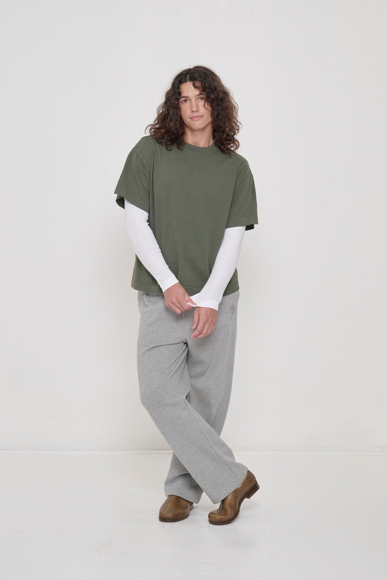 A person in a Pine Boxier Trash Tee over a White Rib Long Sleeve, pulling the long sleeve's cuff.