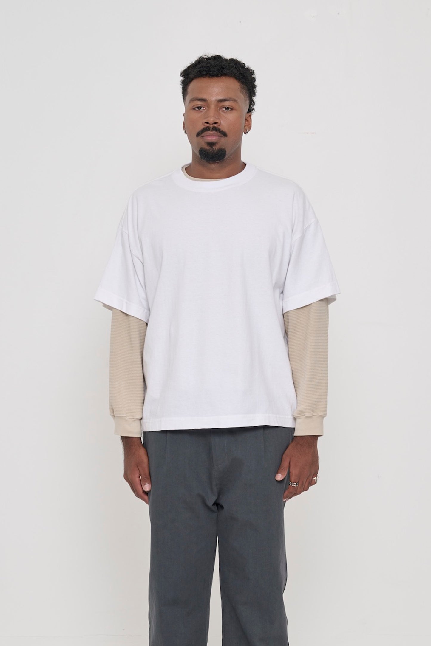 Front view of a 6'2" man wearing a White Boxier Trash Tee in size XL, layered over an Oat thermal. Hem at lower hip.