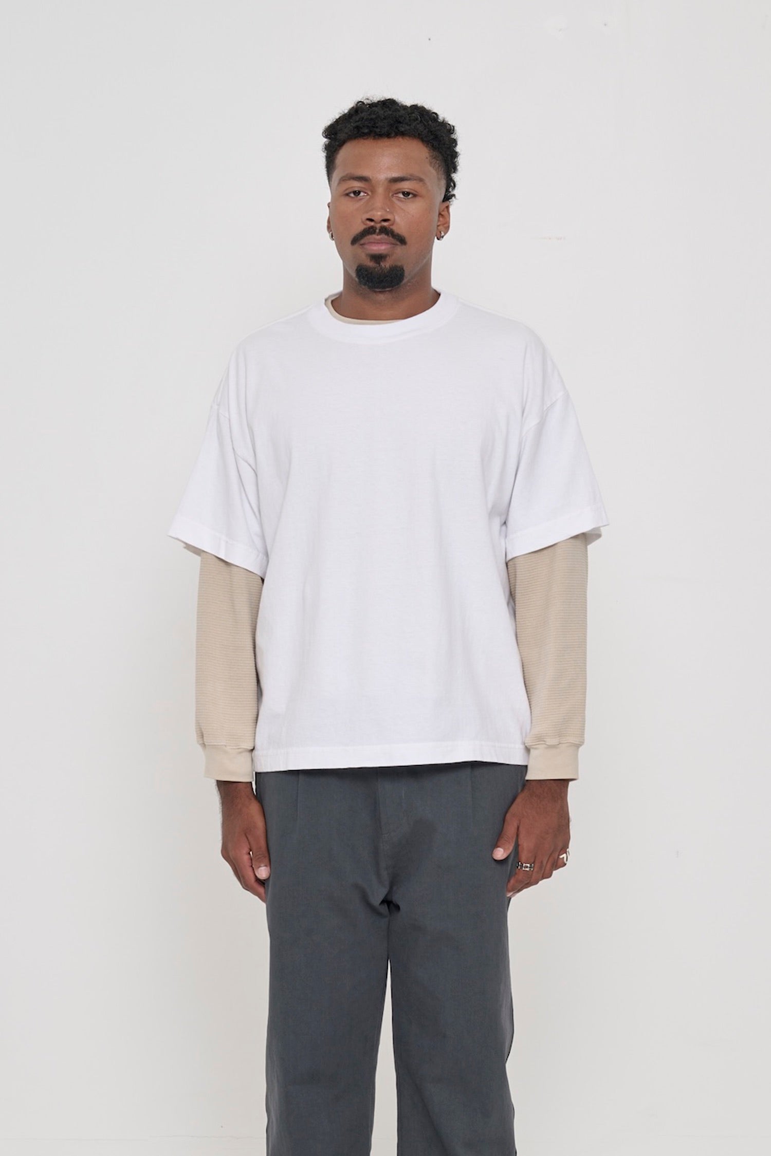 Front view of a 6'2" man wearing a White Boxier Trash Tee in size XL, layered over an Oat thermal. Hem at lower hip.