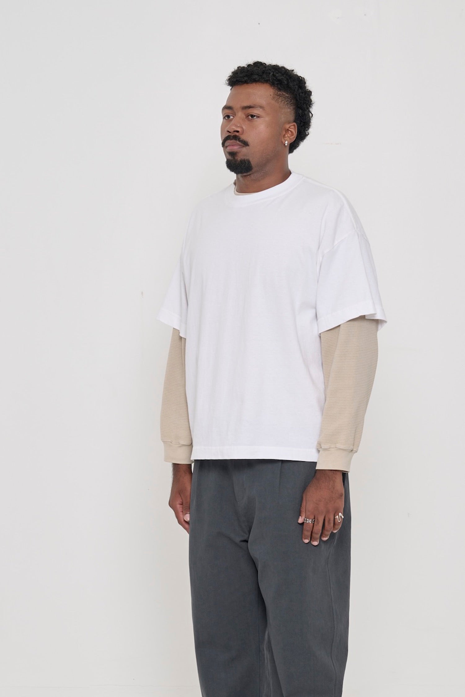 45-degree front view of a man in a White Boxier Trash Tee showing wide short sleeves and no side seams.