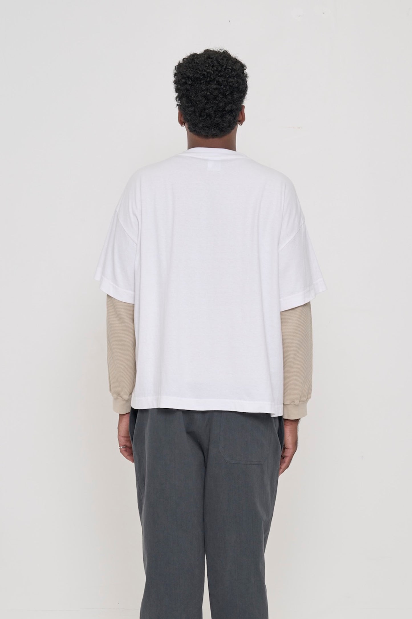 Back view: a man in a White Boxier Trash Tee showing fabric drape and relaxed fit throughout.