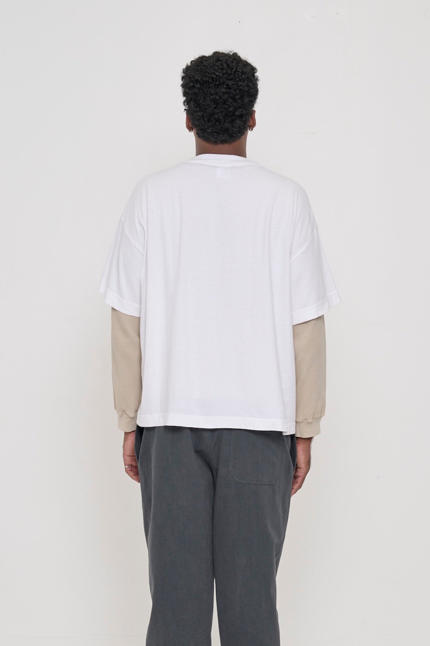 Back view: a man in a White Boxier Trash Tee showing fabric drape and relaxed fit throughout.