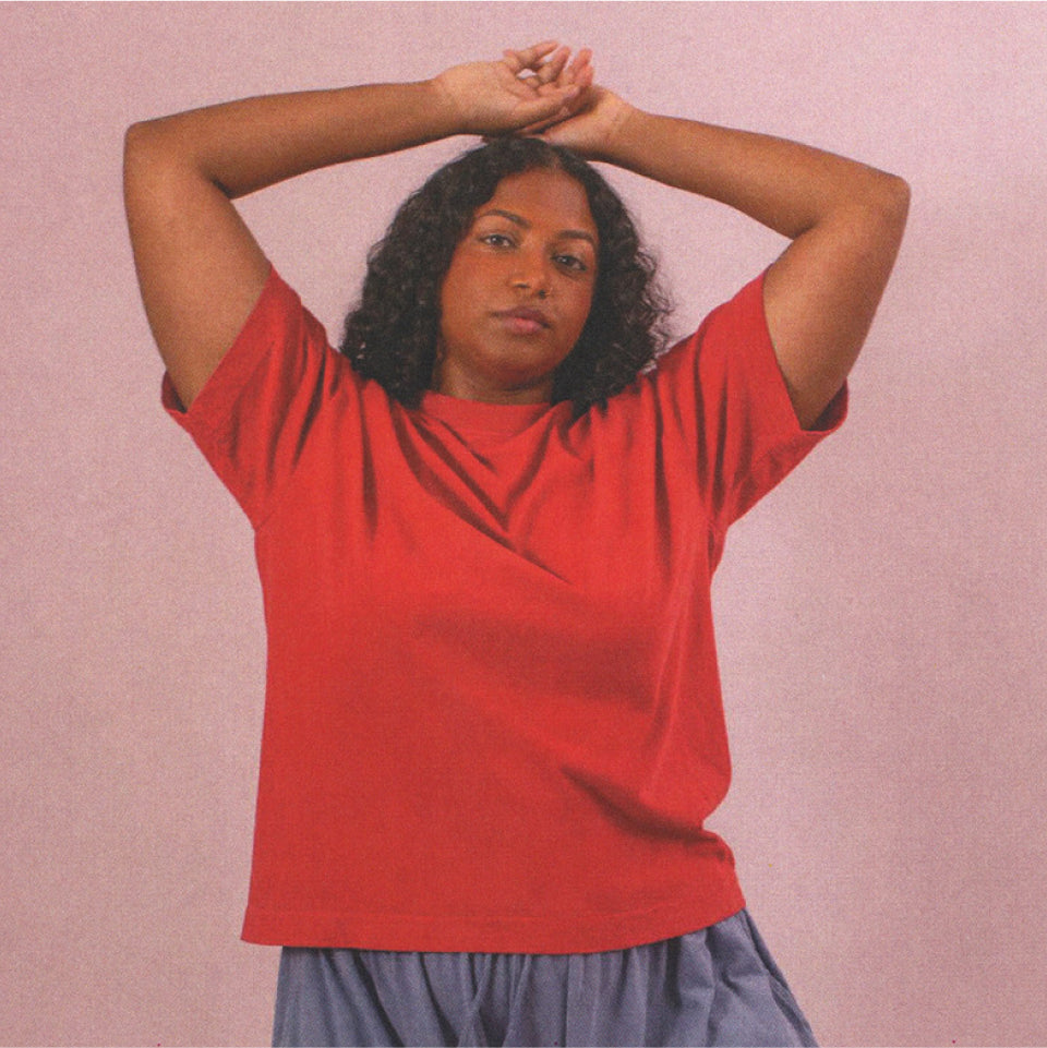 Person wearing a Cedar Boxier Trash Tee and Periwinkle Tubular Pants against a pink background.
