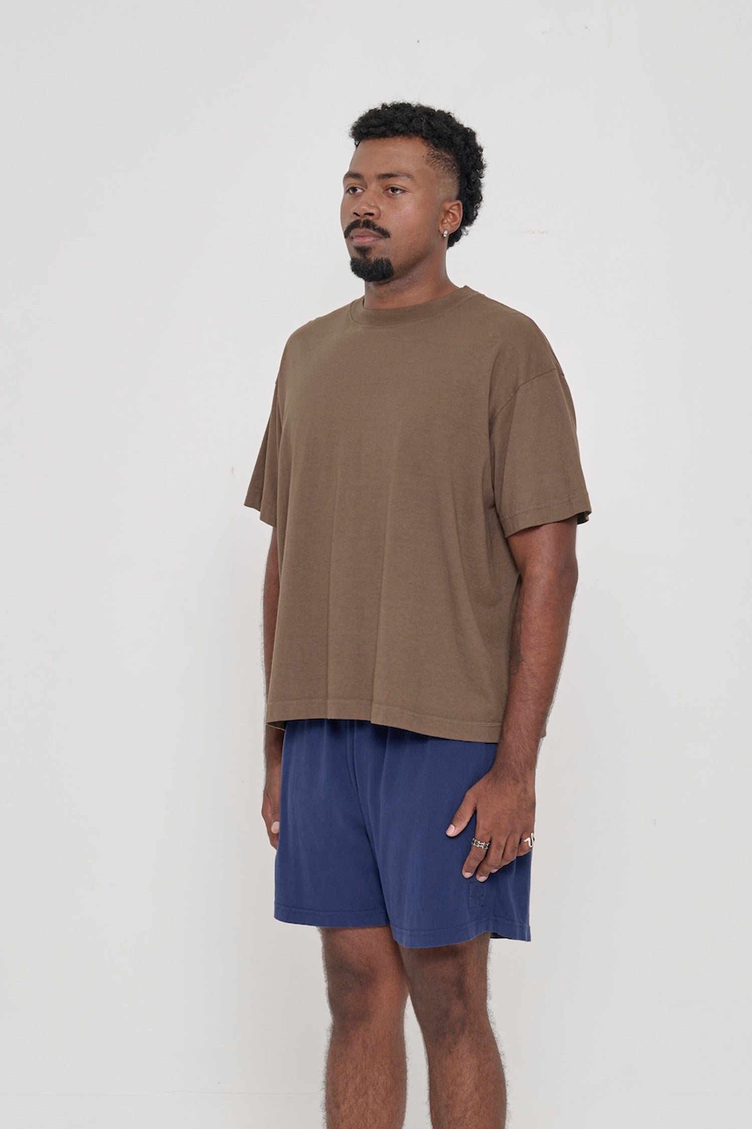 3/4 front view of person in a Dry Soil brown Boxier Trash Tee with no side seams.