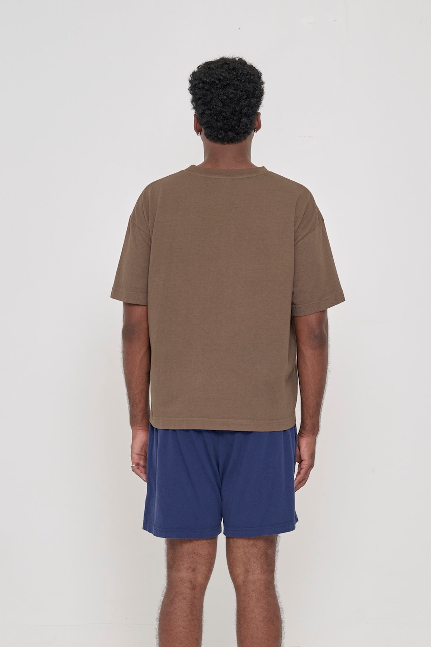 Back view of Boxier Trash Tee in Dry Soil brown showing fabric drape and relaxed fit throughout.