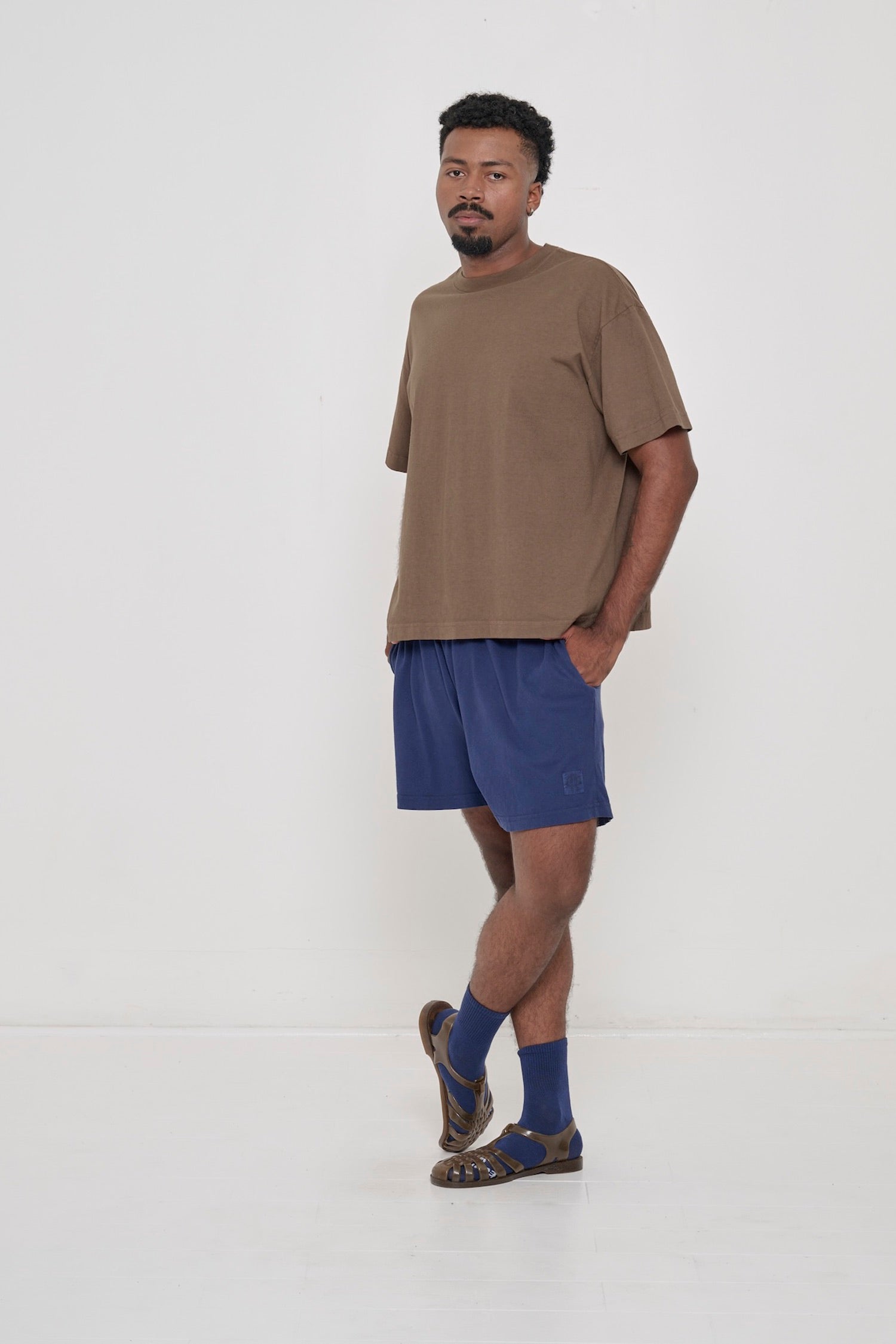 Man wearing Dry Soil brown Boxier Trash Tee with Washed Navy Everyday Shorts.