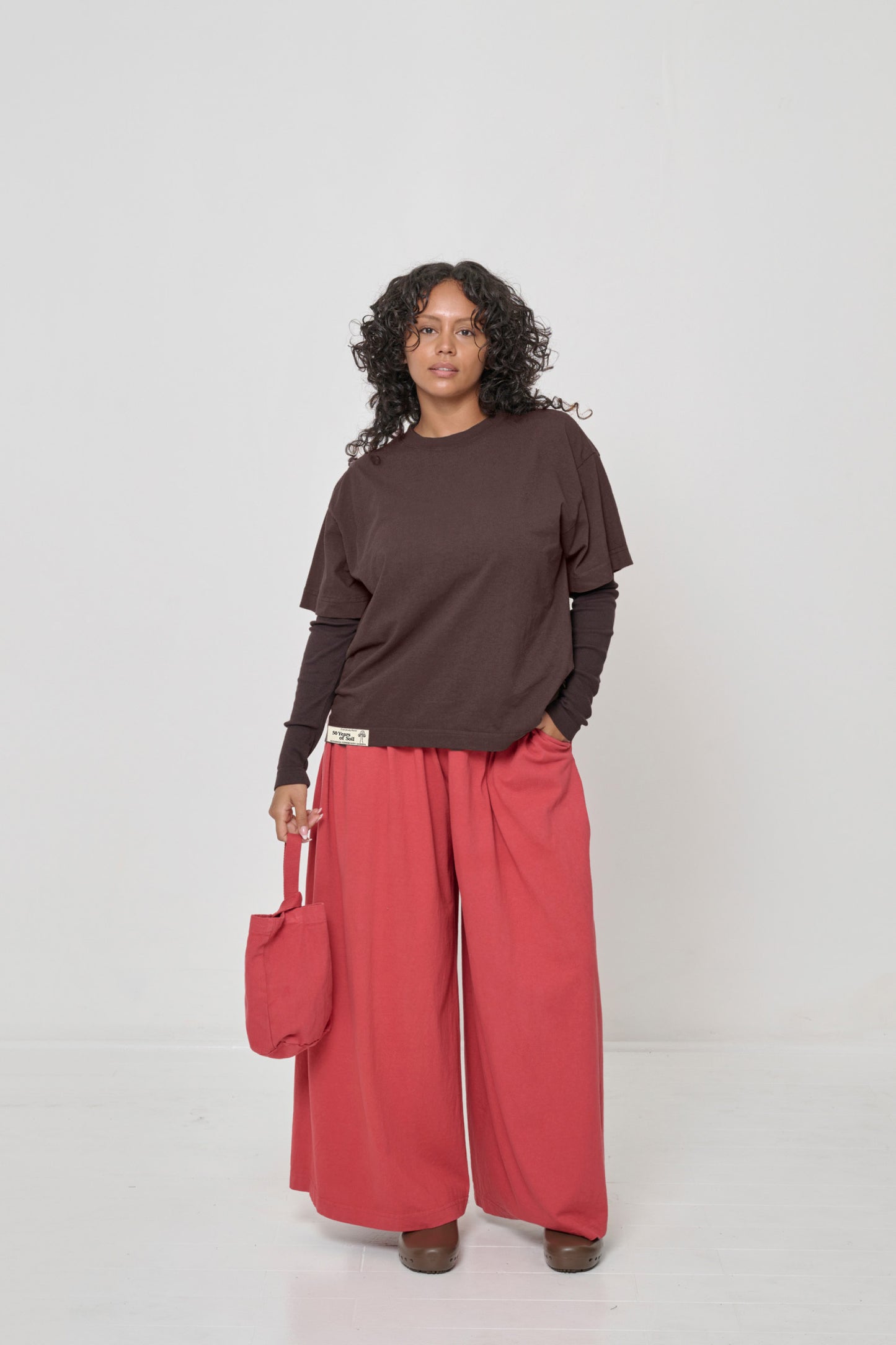 One hand in pocket of Tubular Pants and holding a Loop Tote by her side.