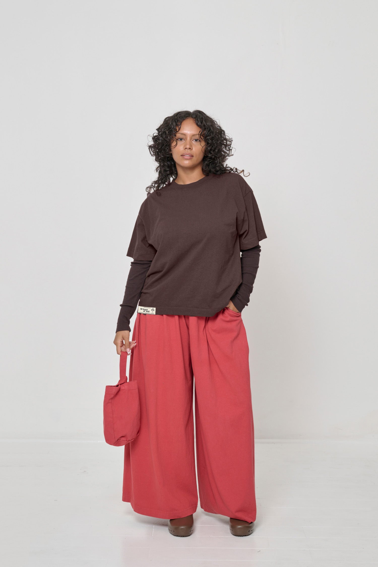 One hand in pocket of Tubular Pants and holding a Loop Tote by her side.
