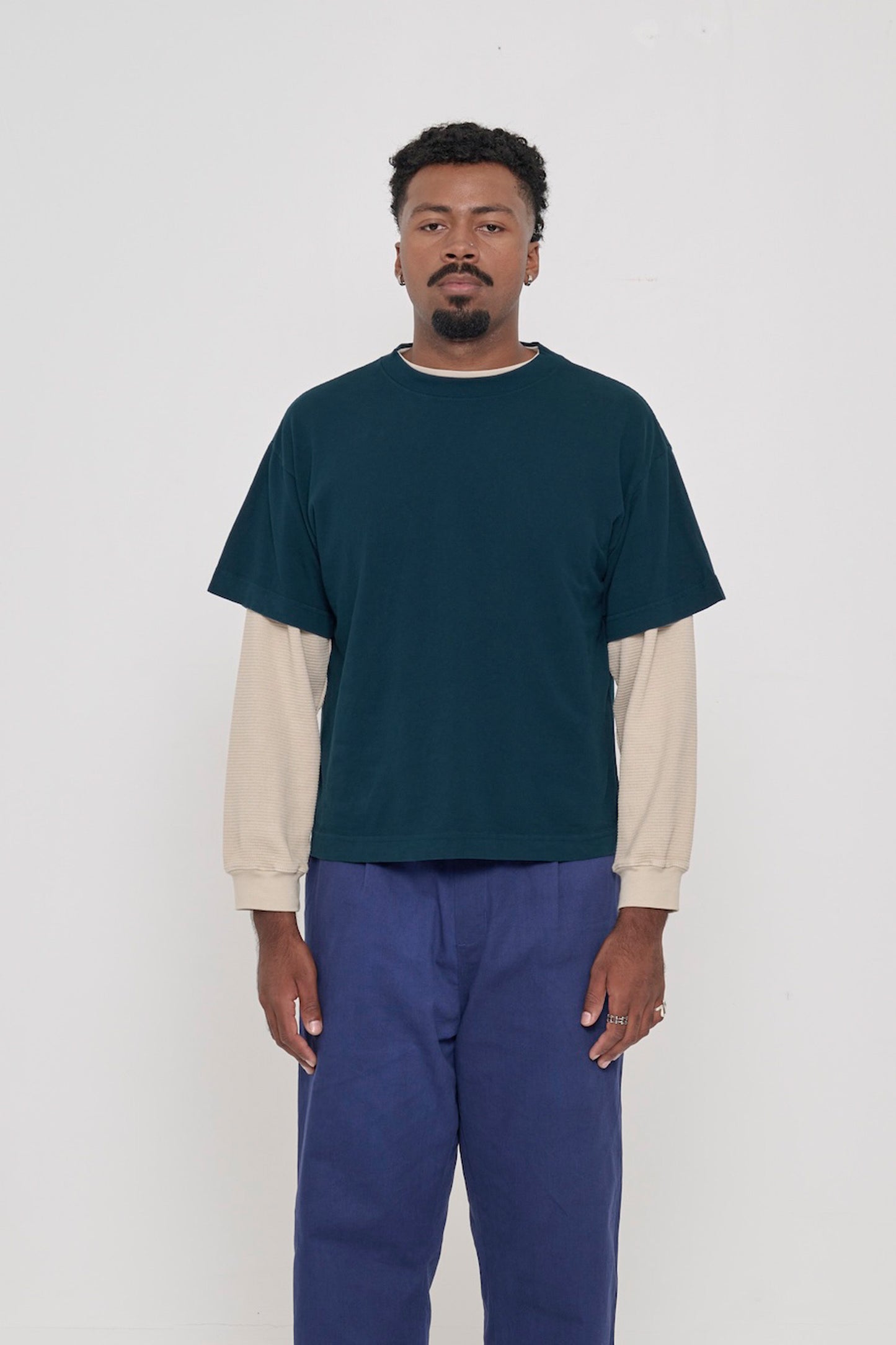 Front view of a man wearing Juniper dark teal Boxier Trash Tee. Bottom hem cropped to the mid upper hip.