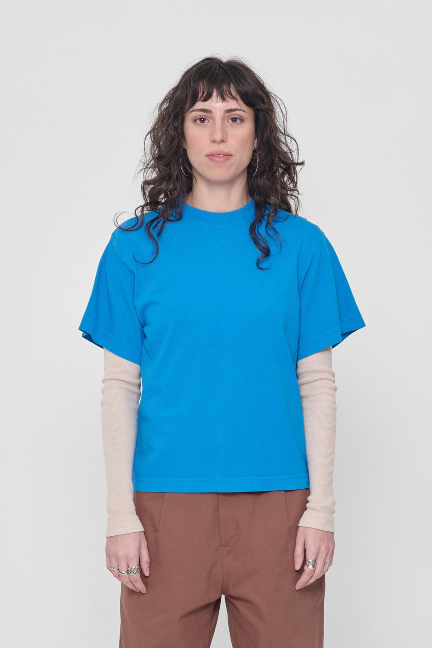 5'6" woman in a size XS Malibu blue Boxier Trash Tee. Hem at her middle hip.