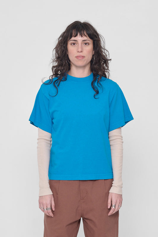 5'6" woman in a size XS Malibu blue Boxier Trash Tee. Hem at her middle hip.