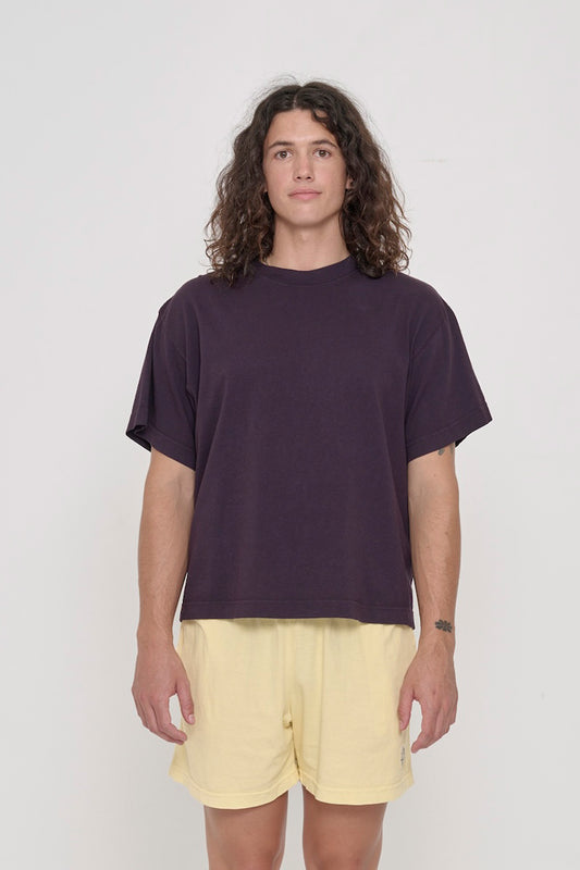 A 6' person in a size M Mulberry dark purple Boxier Trash Tee. Bottom hem at the mid upper hip.