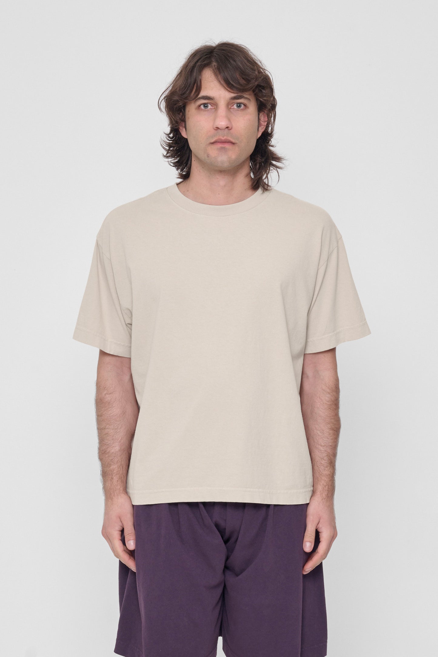 A 6'2" man in a size L Oat beige Boxier Trash Tee. Bottom hem at the middle hip.