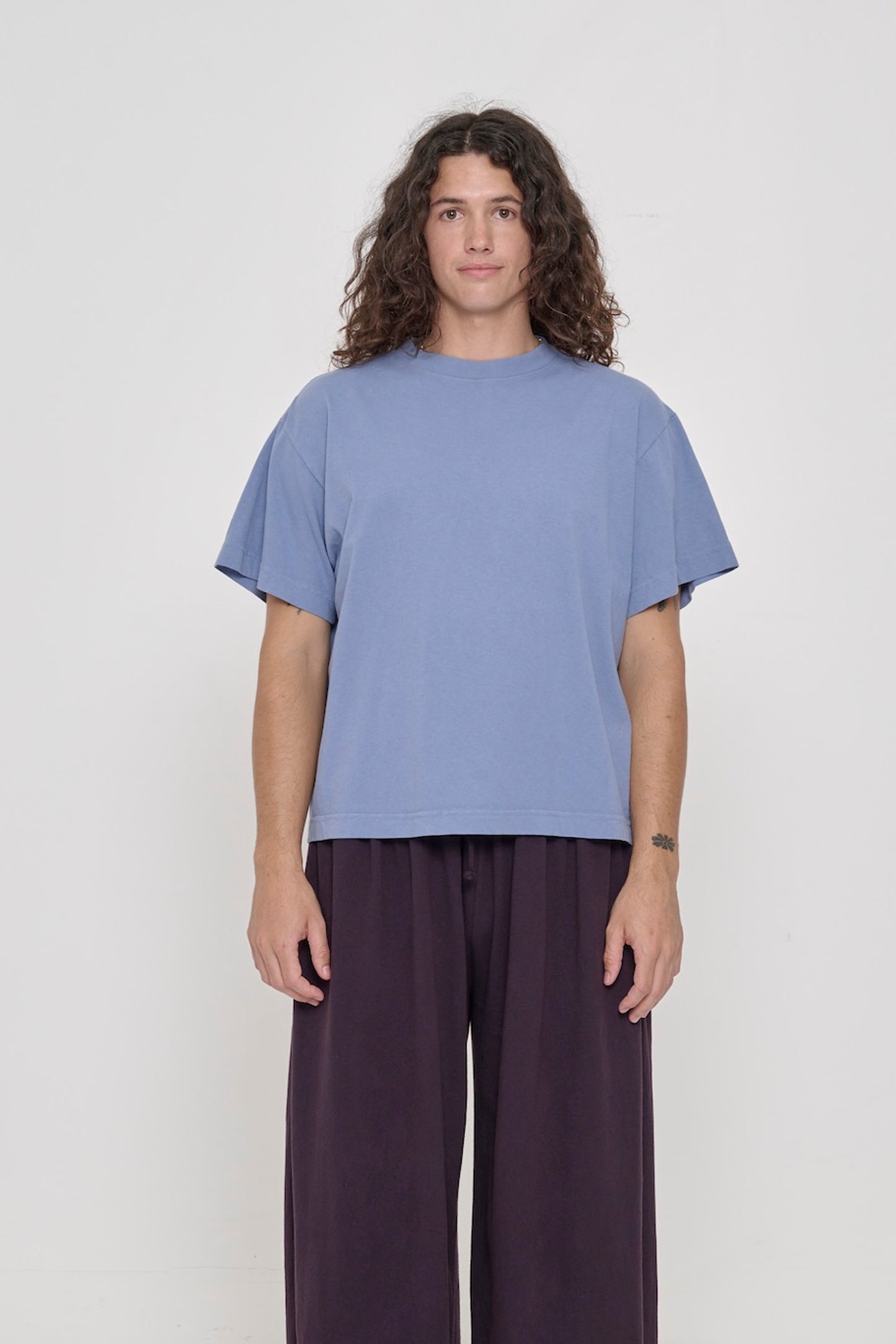 Front view of a person wearing Periwinkle light blue-purple Boxier Trash Tee. Bottom hem cropped to the mid upper hip.