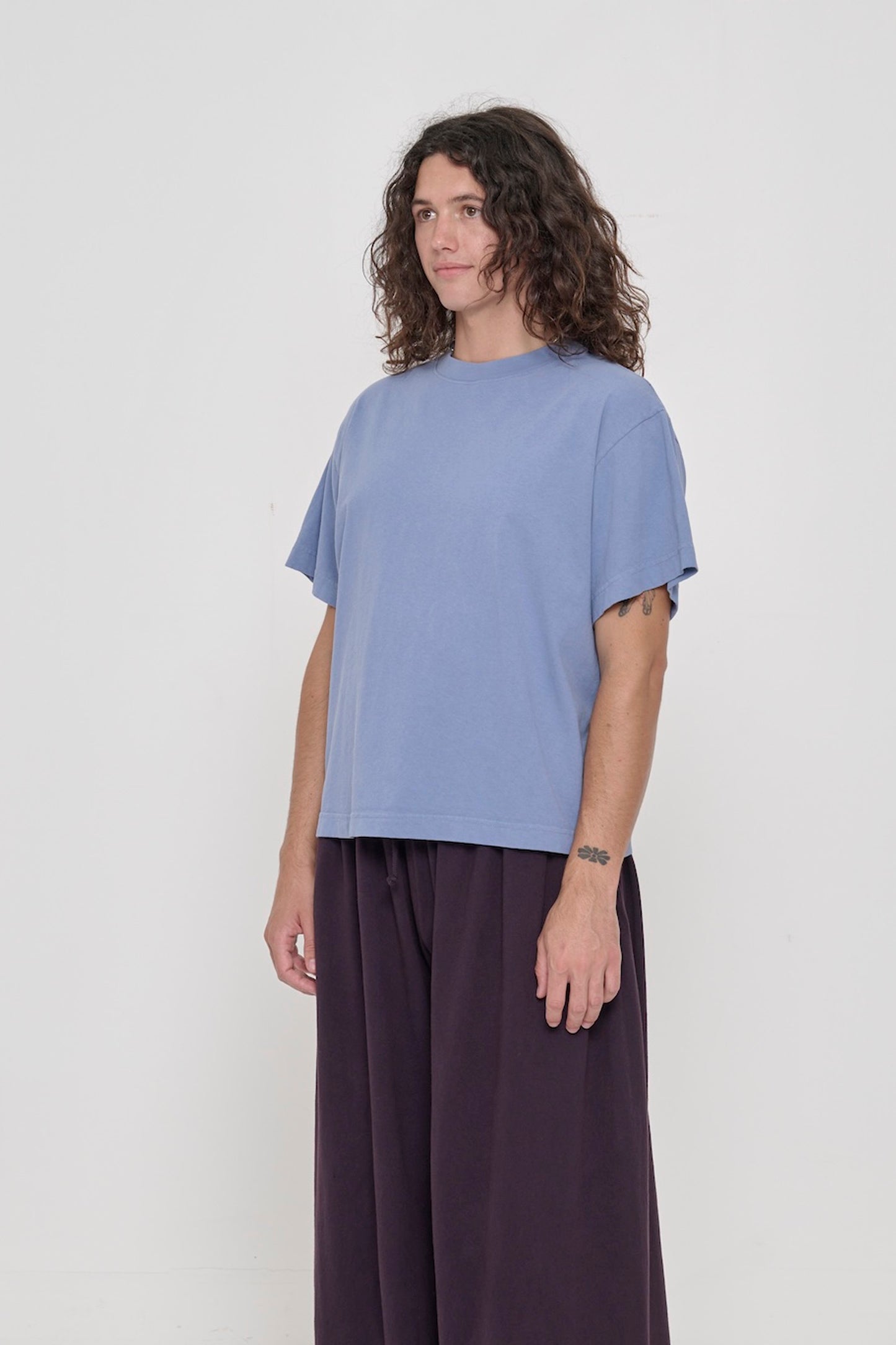 3/4 front view of person wearing Periwinkle Boxier Trash Tee with no side seams and wider than classic short sleeves. 
