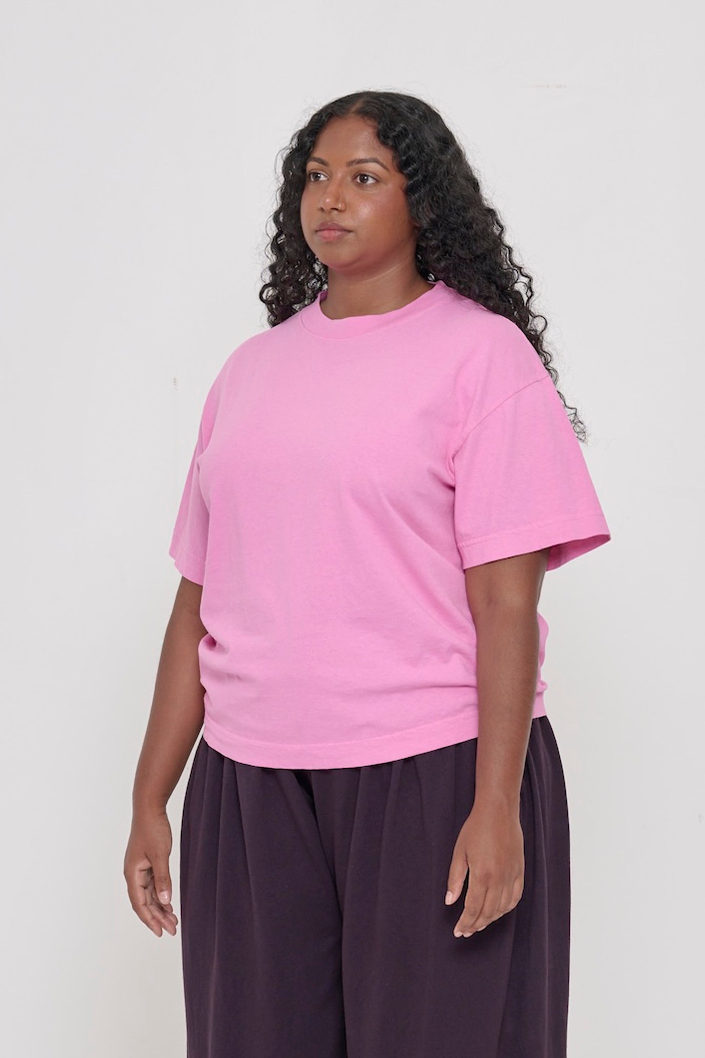 3/4 front view of person wearing Pixie light pink Boxier Trash Tee with no side seams and wider than classic short sleeves. 