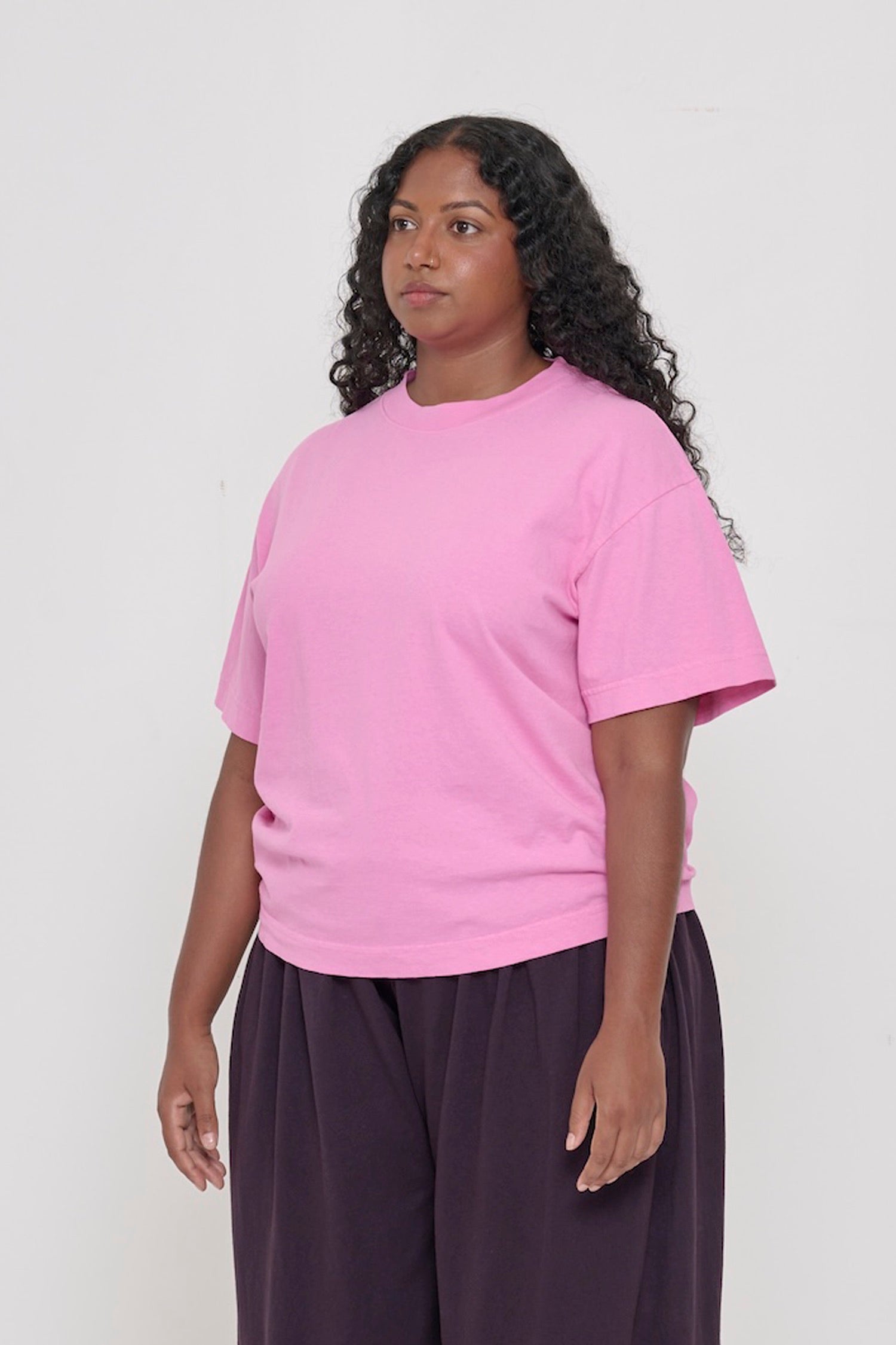 3/4 front view of person wearing Pixie light pink Boxier Trash Tee with no side seams and wider than classic short sleeves. 