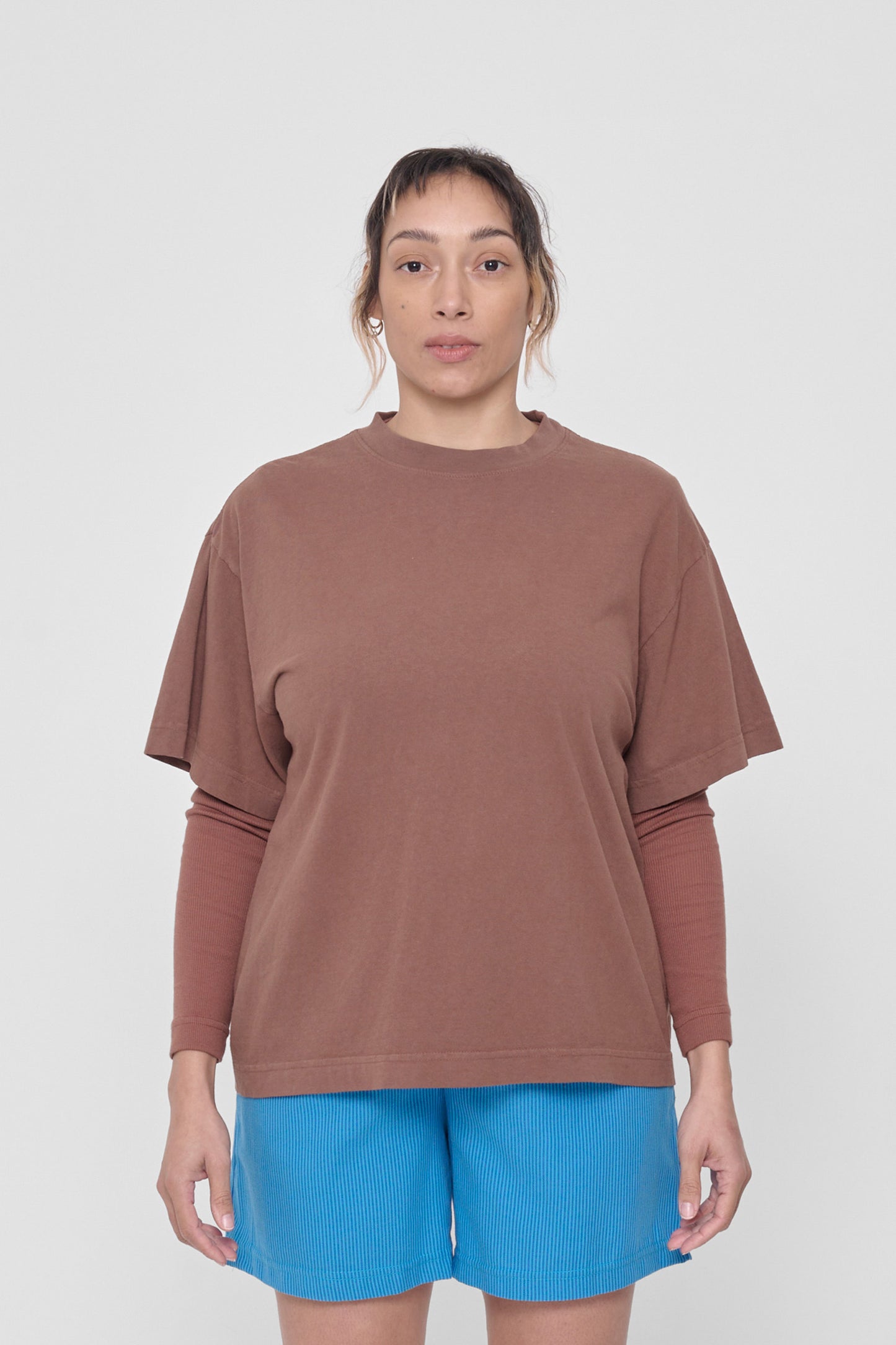 A 5'4" woman in a size M Potting Soil Boxier Trash Tee. Hem at her lower hip.