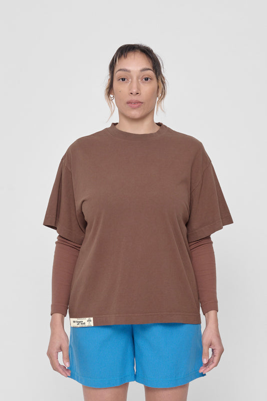 A 5'4" woman in a size M Potting Soil Boxier Trash Tee. Hem at her lower hip.