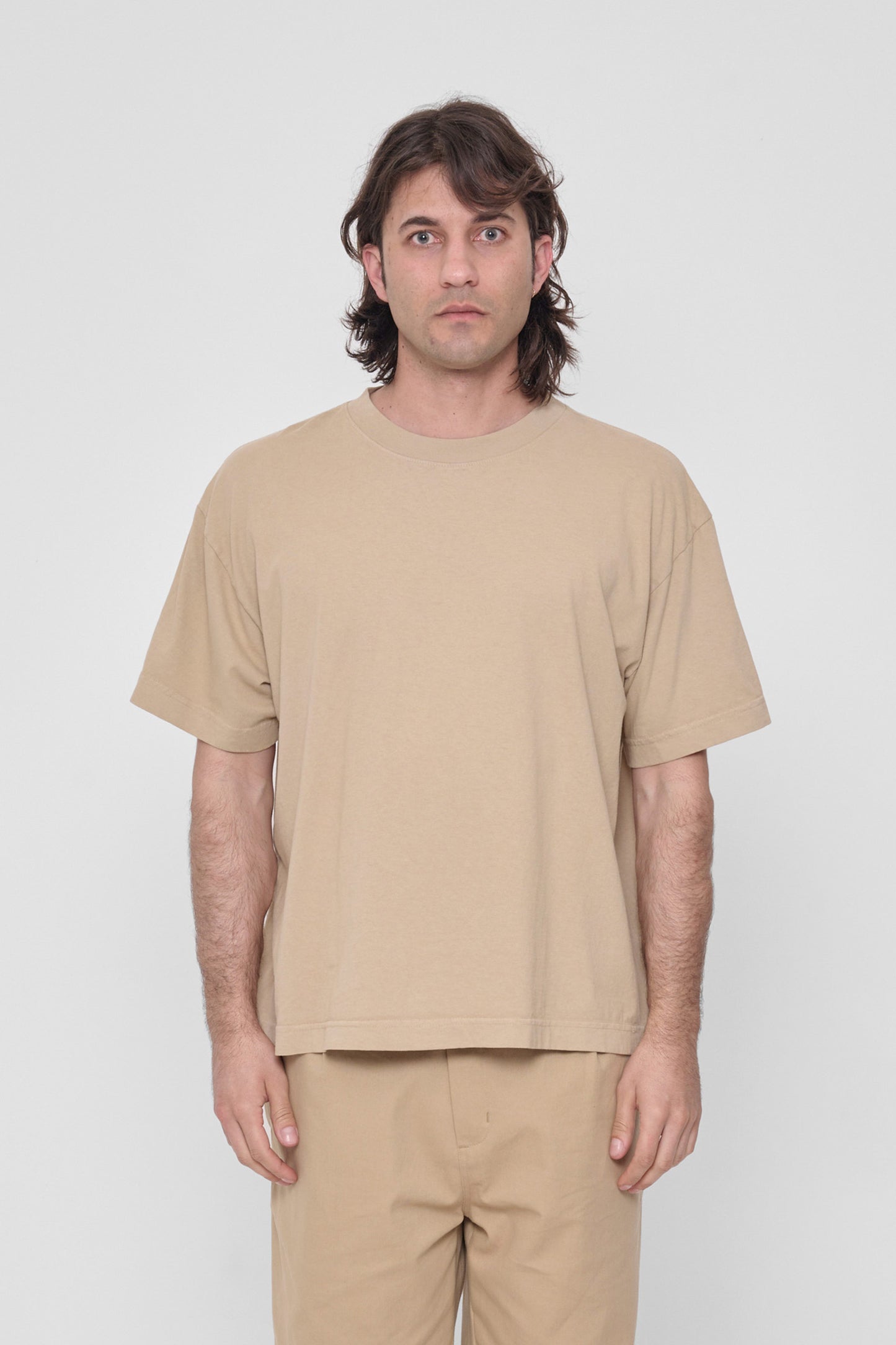 A 6'2" man in a size L Sand Storm khaki Boxier Trash Tee. Hem at middle hip.