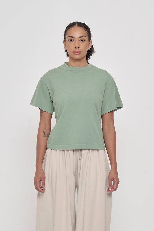Front view of a woman wearing Wasabi light green Boxier Trash Tee. Bottom hem cropped to the mid upper hip.