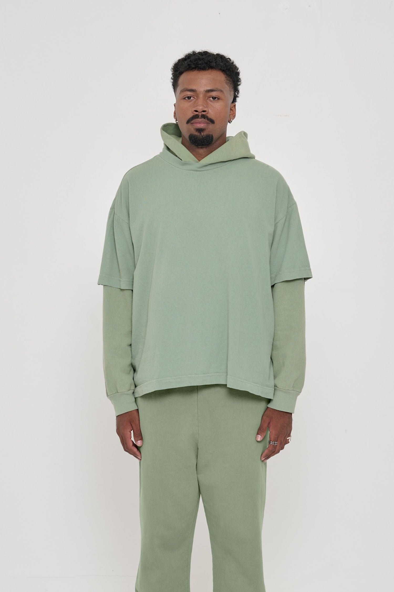 Front view of a man wearing Wasabi light green Boxier Trash Tee. Bottom hem cropped to the mid upper hip.