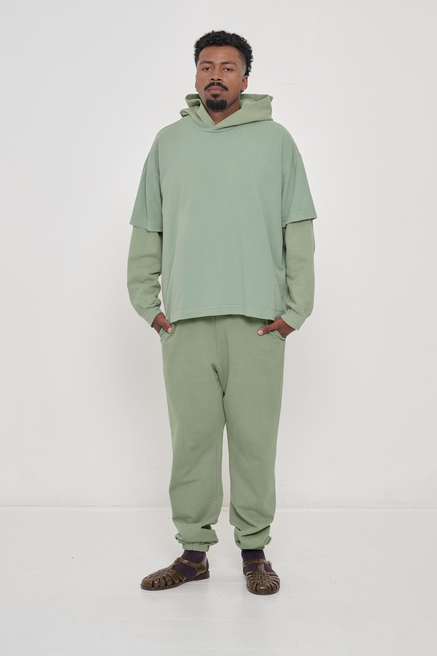Man wearing Wasabi light green Boxier Trash Tee layered on top of Wasabi Trash Hoodie and Wasabi Trash Sweatpants.