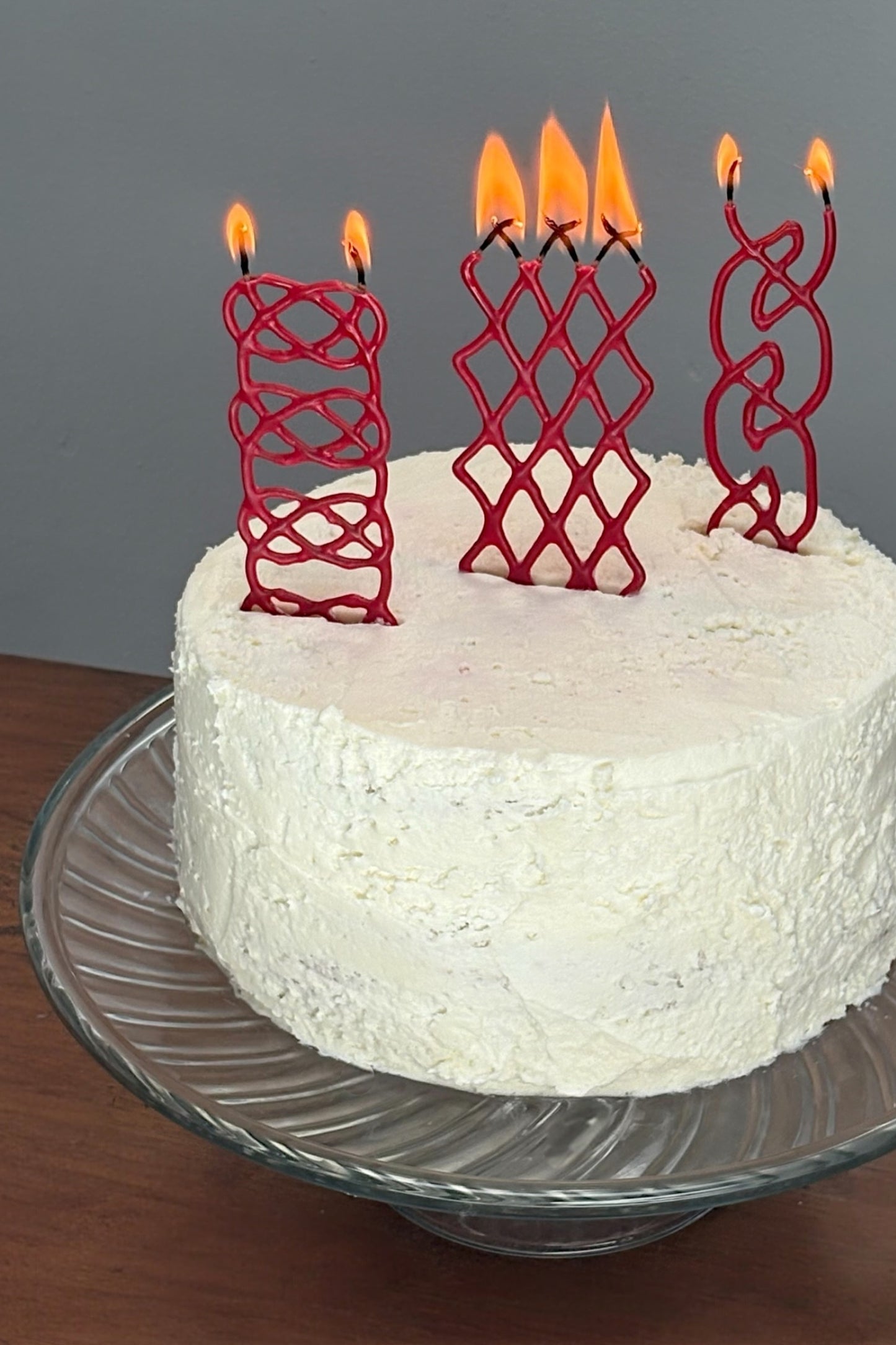 White cake with red braided candles on a gray background