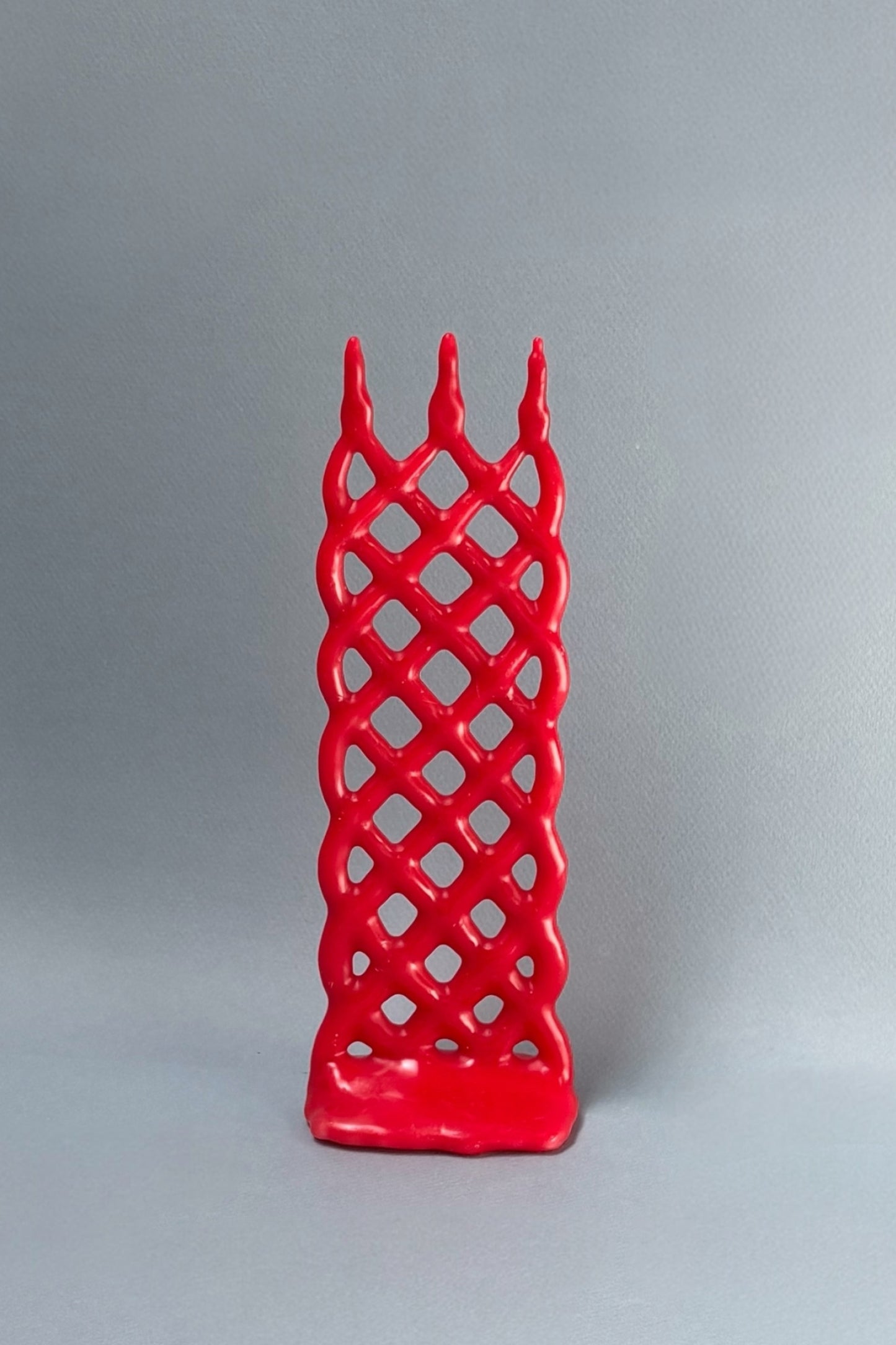 Red lattice-patterned candle on a gray background