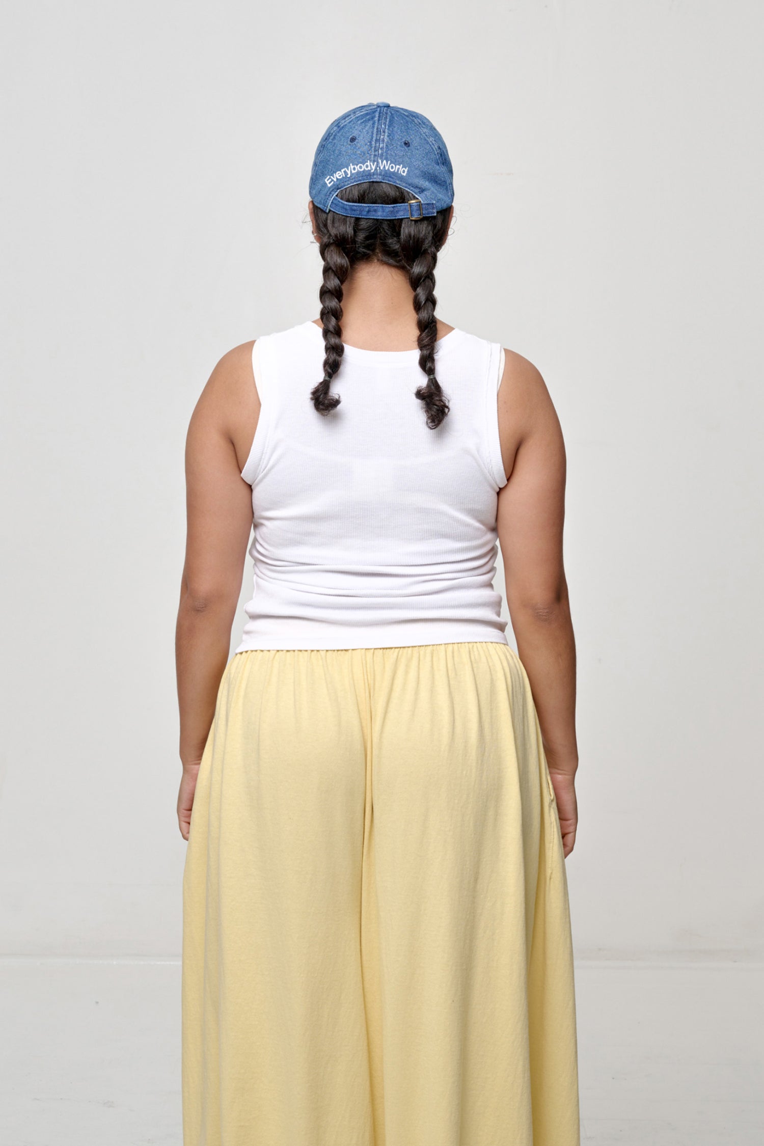 Woman wearing Bucky Logo Cap in Denim blue with 'Everybody,World' text embroidered in an arc above the adjustable closure. 