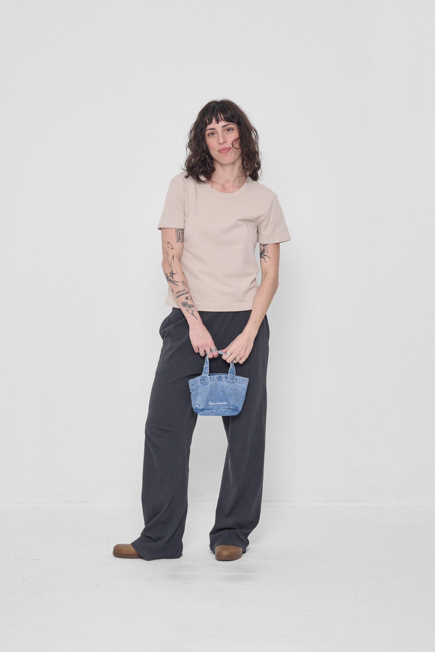 Held by a model who's wearing an Oat Tailored Trash Tee and Slate Apartment pants.