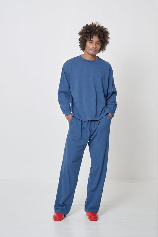 Man wearing a matching dark blue long sleeve tee and Apartment Pants set with Red Calzuro Classic Clogs.