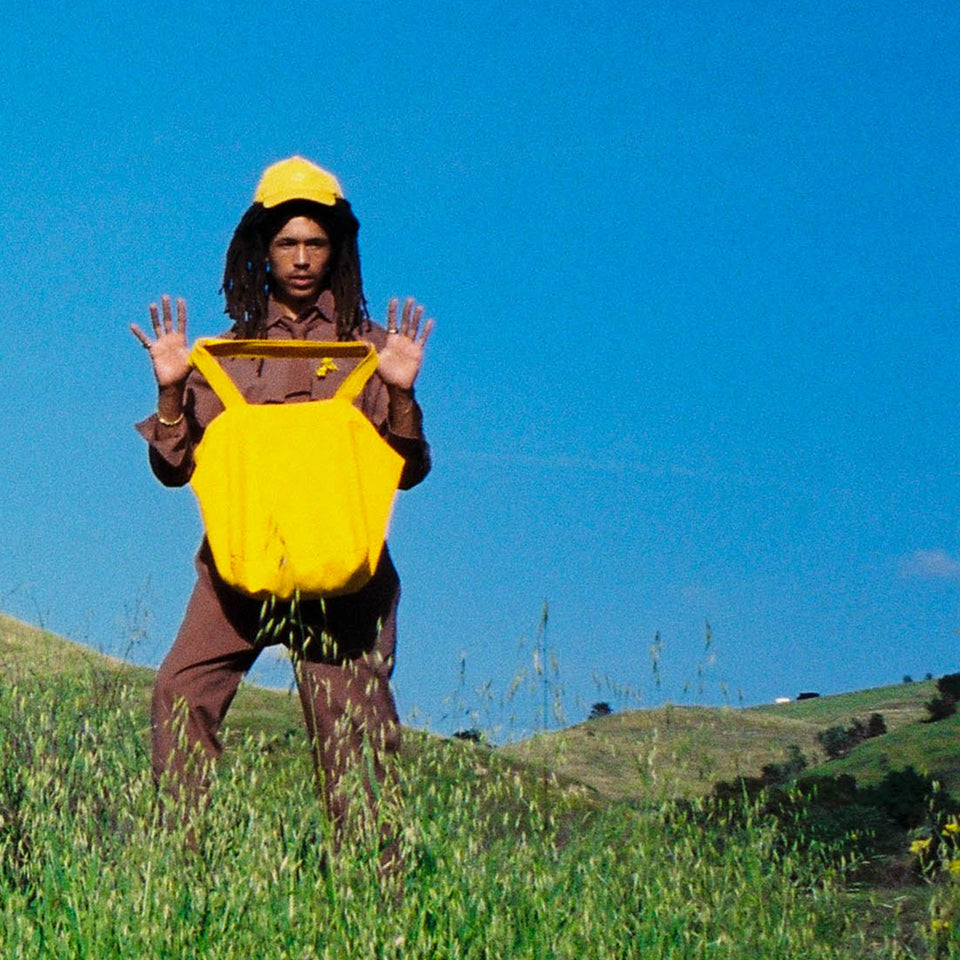 Man in a field holding up a Big Tote in Everybody Yellow.