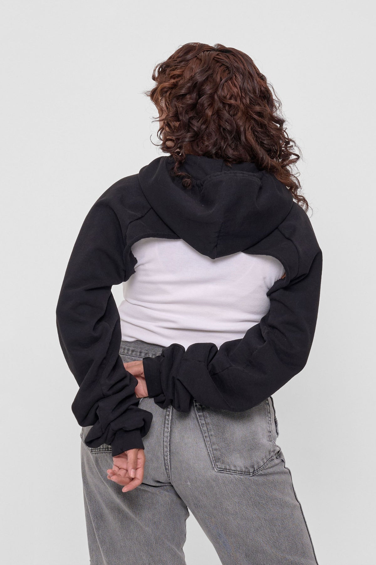 Clyde x Everybody.World Hoodie Scarf in Black – back view on model, hood down and arms behind the back