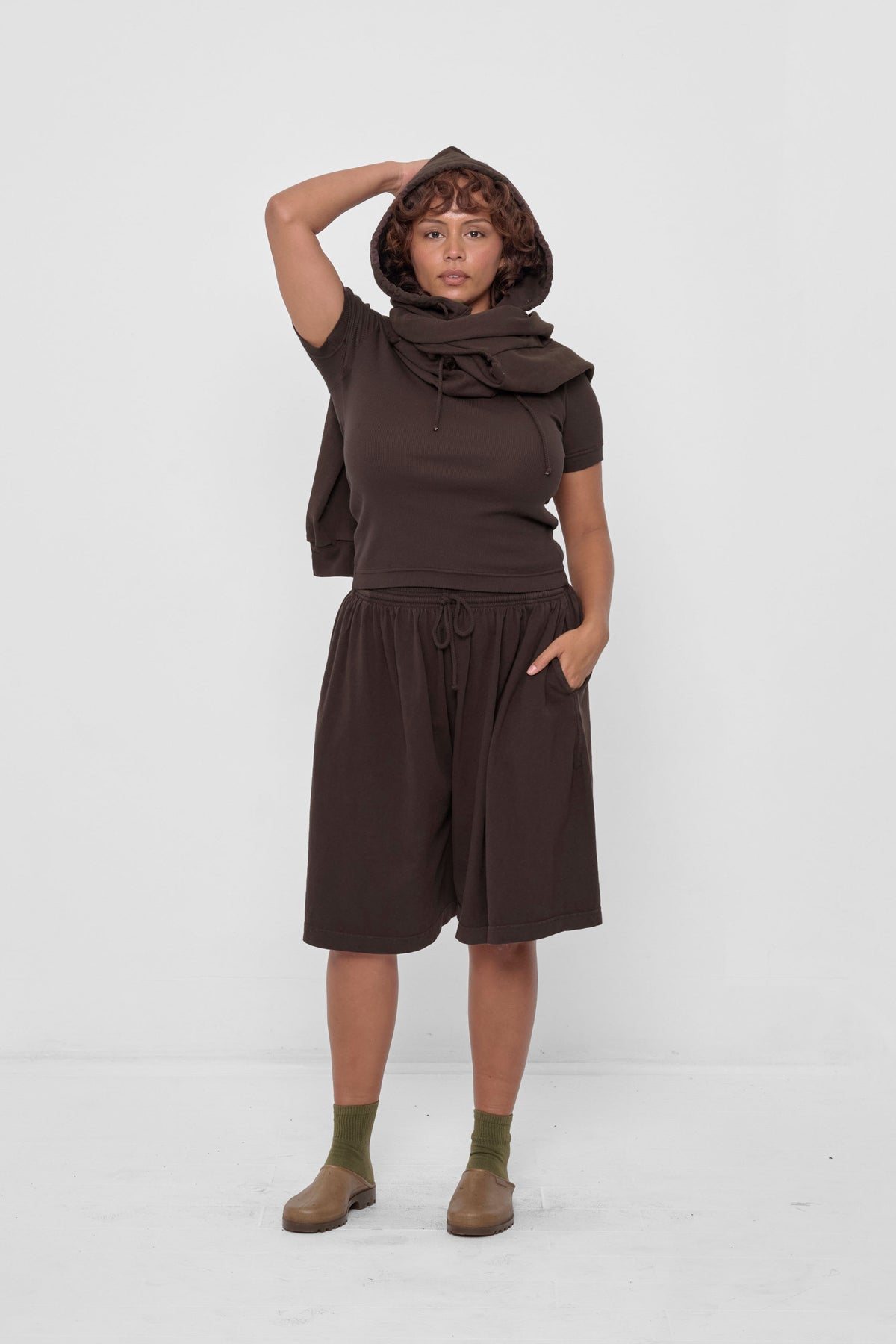 Clyde x Everybody.World Hoodie Scarf in Wet Soil – front view, styled with Wet Soil Long Tubular Shorts, Olive Squishy Socks, and Plasticana Gardana Clogs
