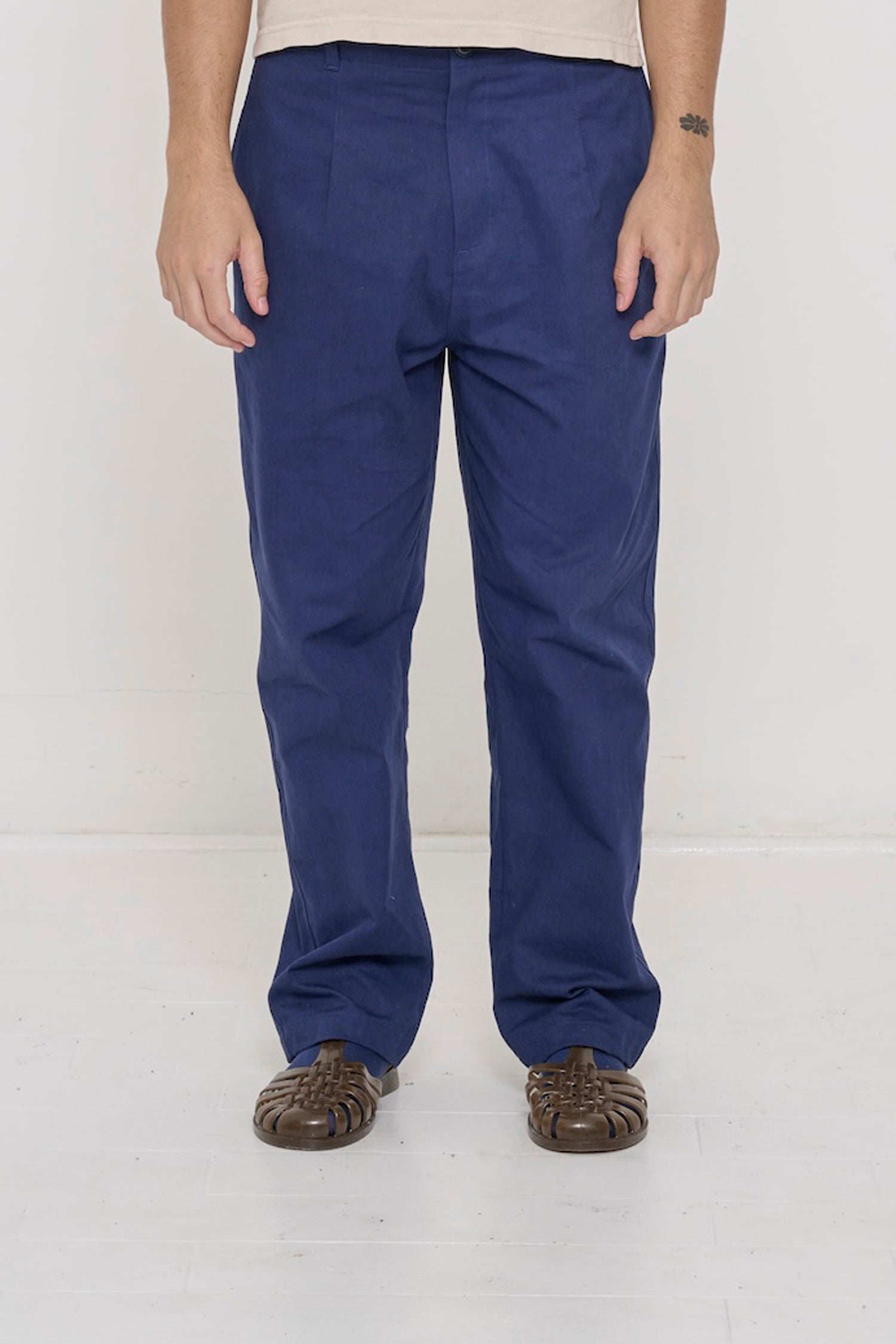 Bottom half of a person in Washed Navy Cotton Twill Life Uniform Pants. Shows relaxed slim silhouette, pleats, belt loops.